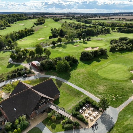 A clubhouse with outside seating and then you can see the golf club from the air.
