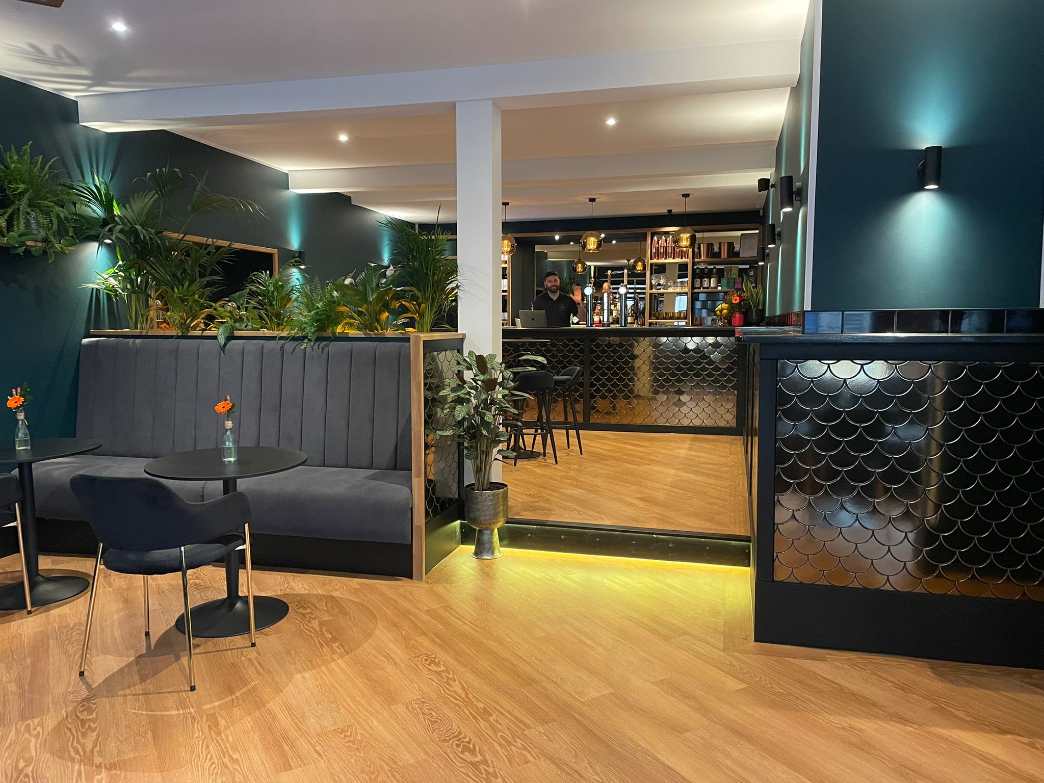 The internal of Alchemy Bar & Lounge. A wooden floor, dark painted walls. Comfy seating and black tables.