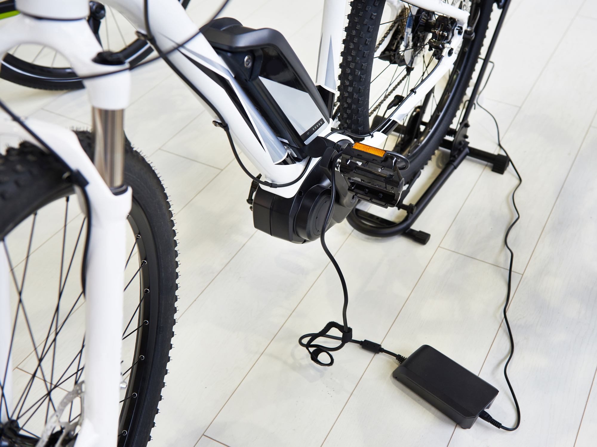 A cropped photo of a white electric bike on charge