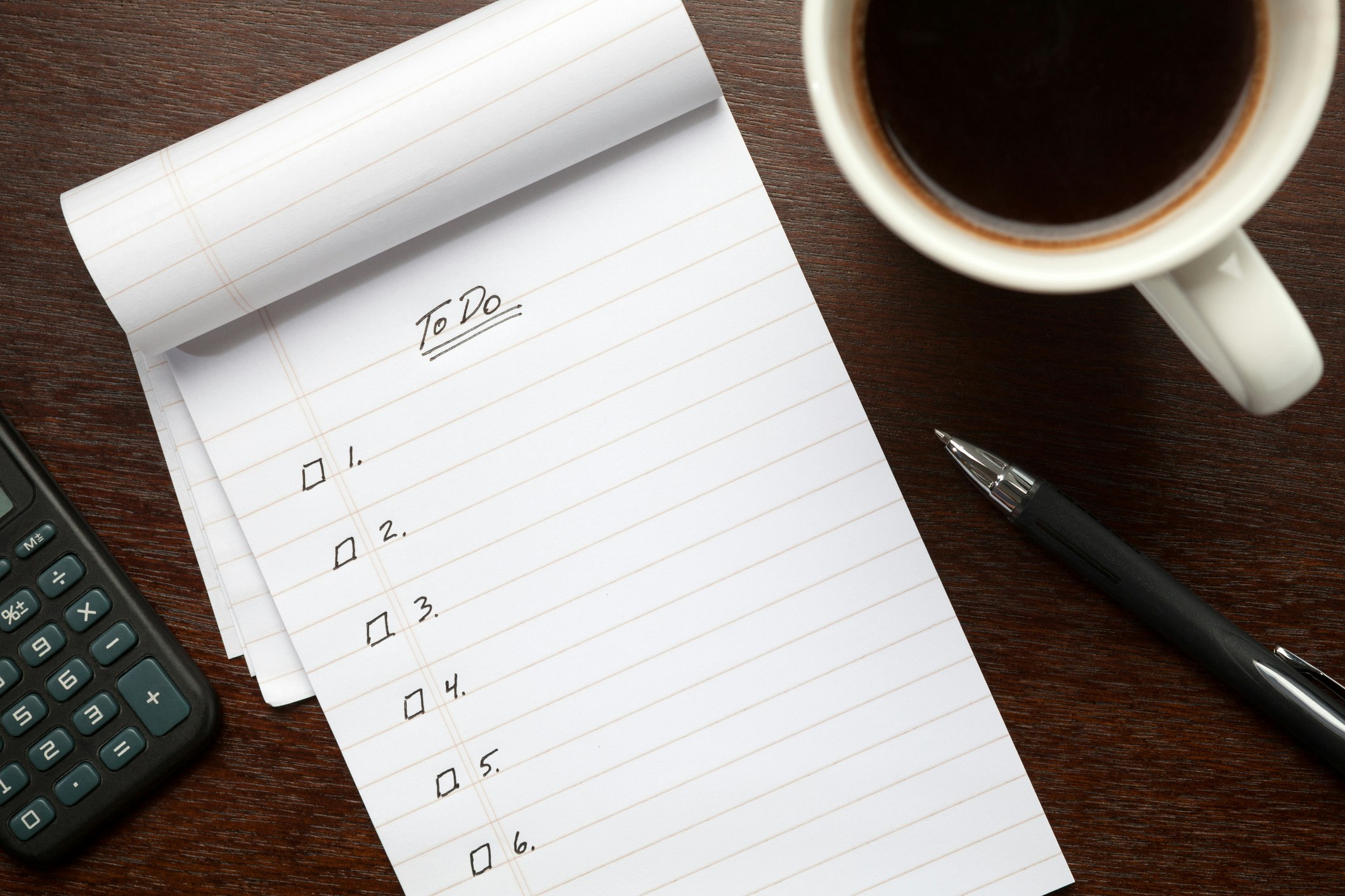 Getty image of a to do list, a cup of coffee and a pen. You can also see a calculator to the side.