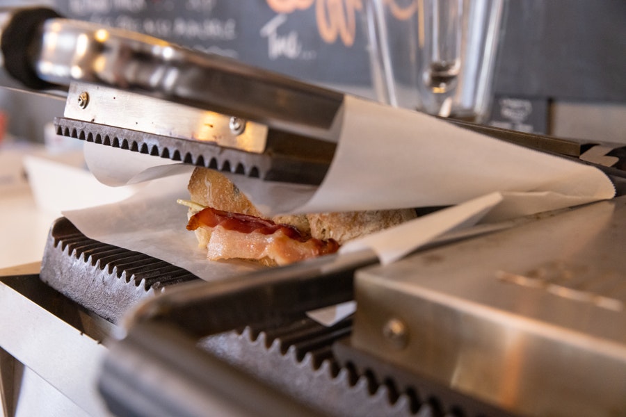 A close up photograph of a sandwich being toasted in a metal toastie maker.