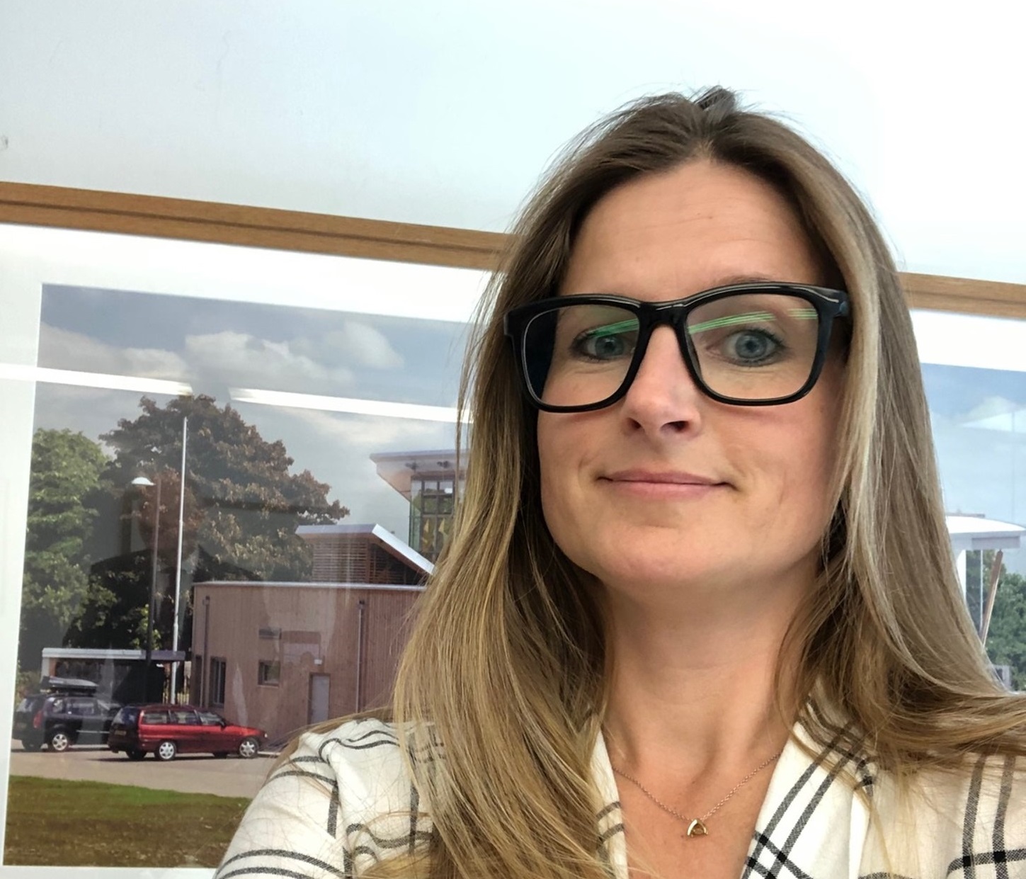 A female looks at the camera and has a picture behind.