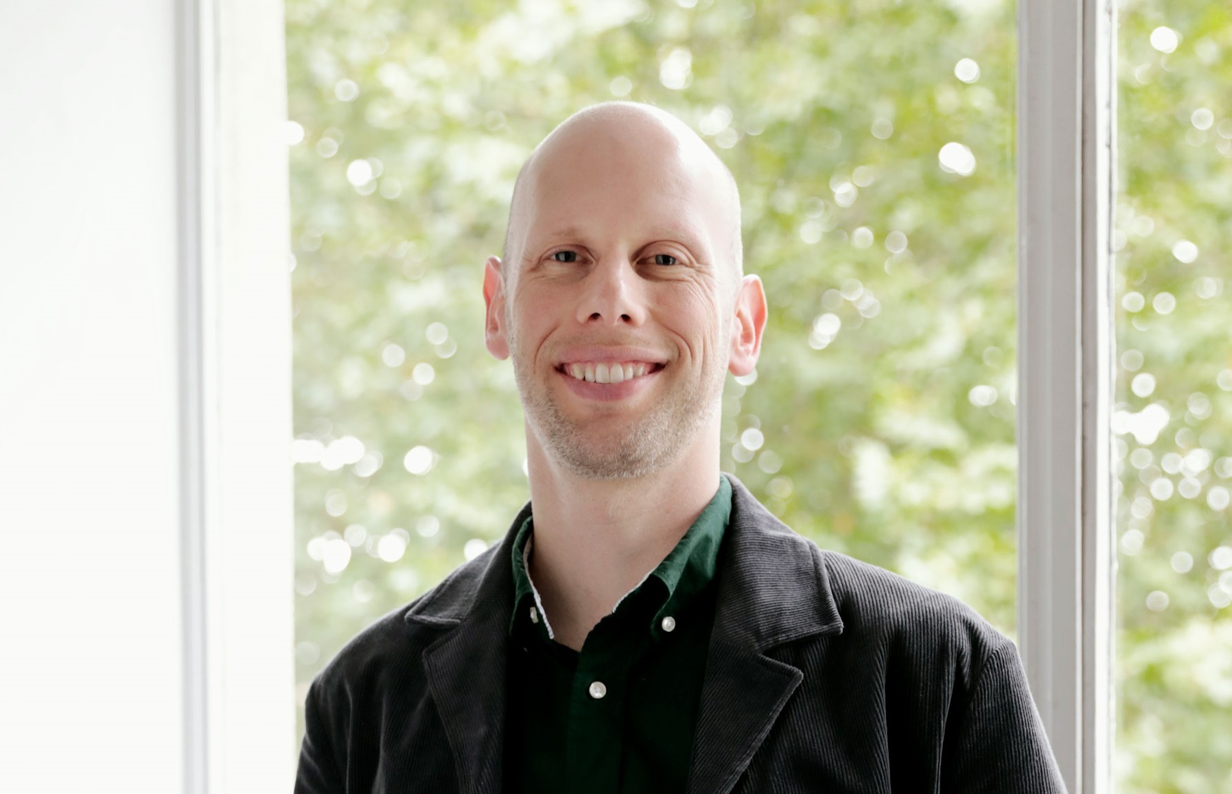 A male wears dark clothes and looks at the camera