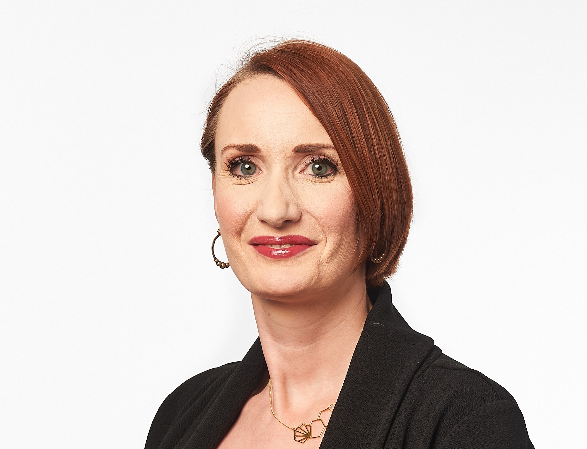 A female wears a black jacket and looks at the camera with a white background.