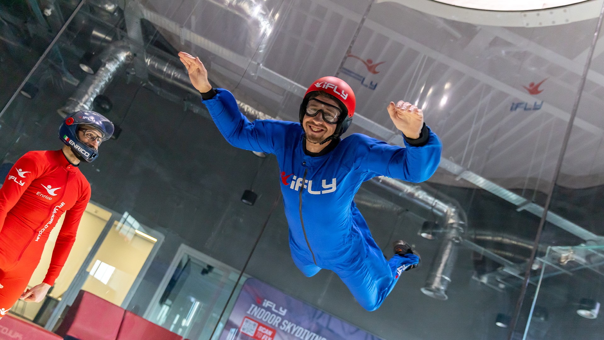 A person is flying in the air and an instructor is next to them.