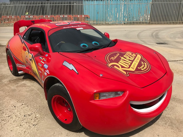 Lighning McQueen from the movie cars. A red race car with yellow writing Rusteze.