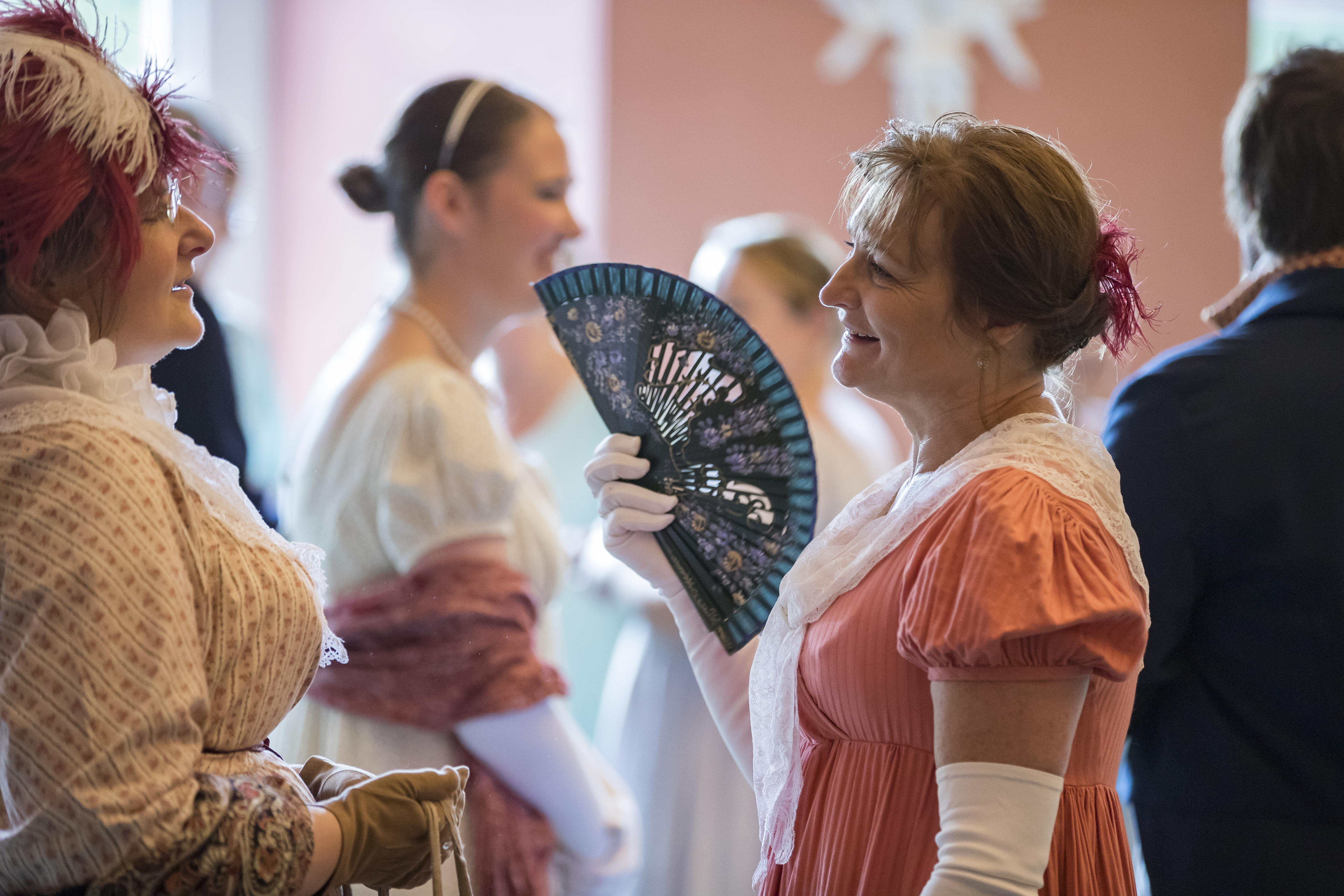 Womens smiling and talking wearing regency-style outfits
