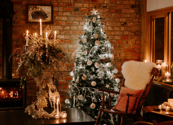 A christmas tree covered in white and silver decorations in a cosy room at Silchester Farm.
