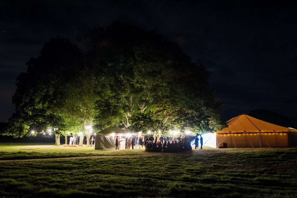 A marquee at night with people standing outside.