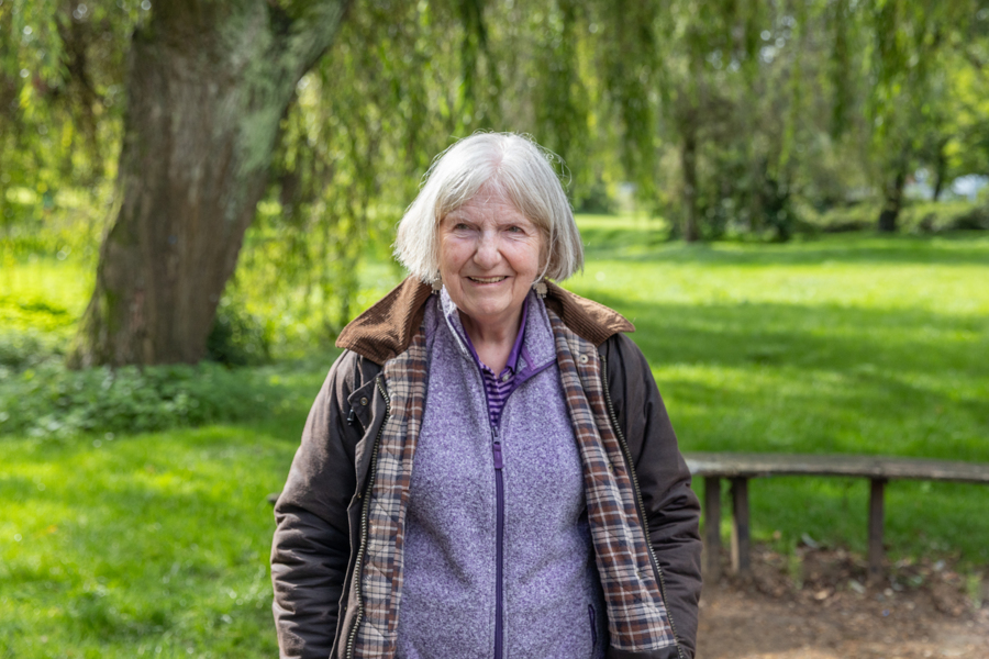A female stands outside with the park behind her.