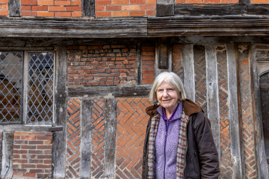 A female stands outside with a building behind her.