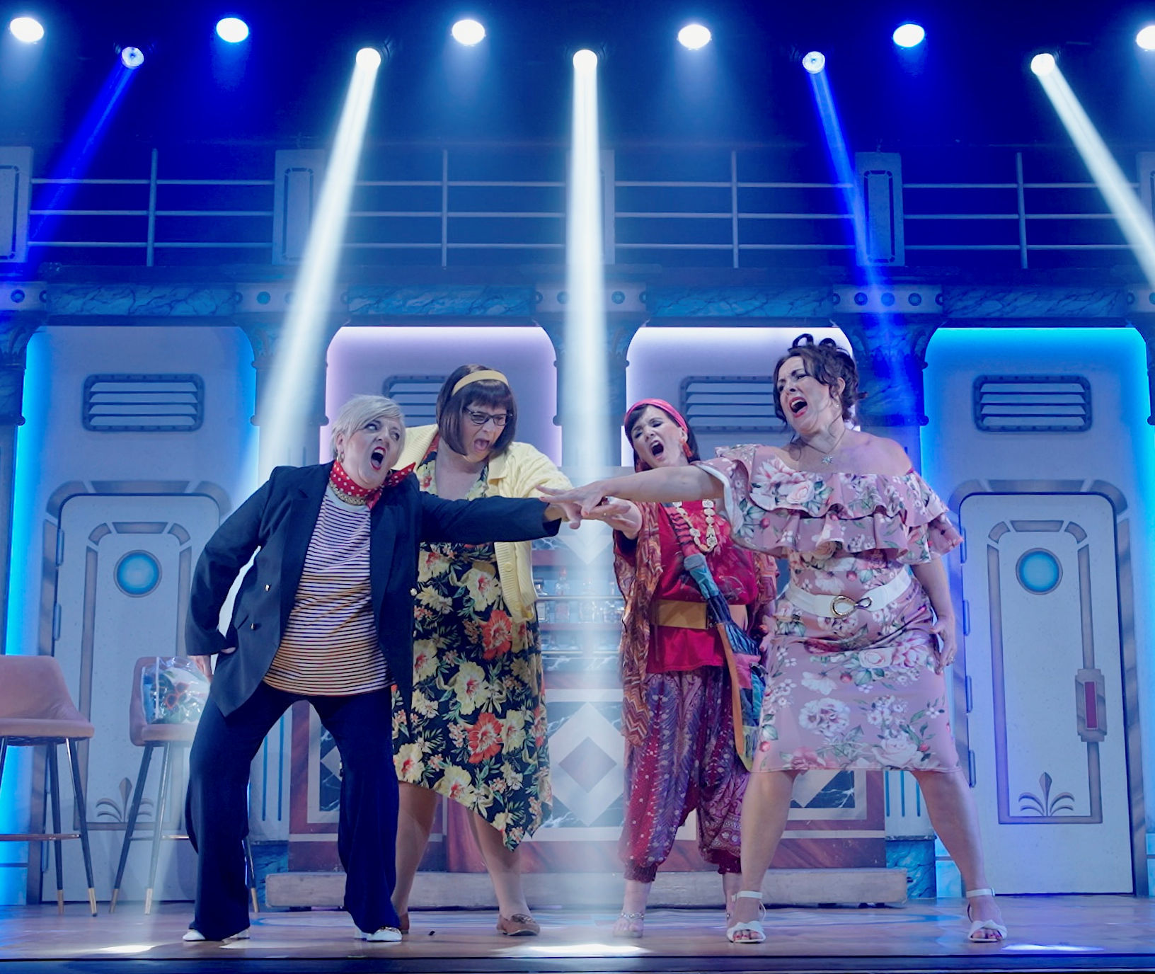 4 females stand on a stage and have their hands in the middle.