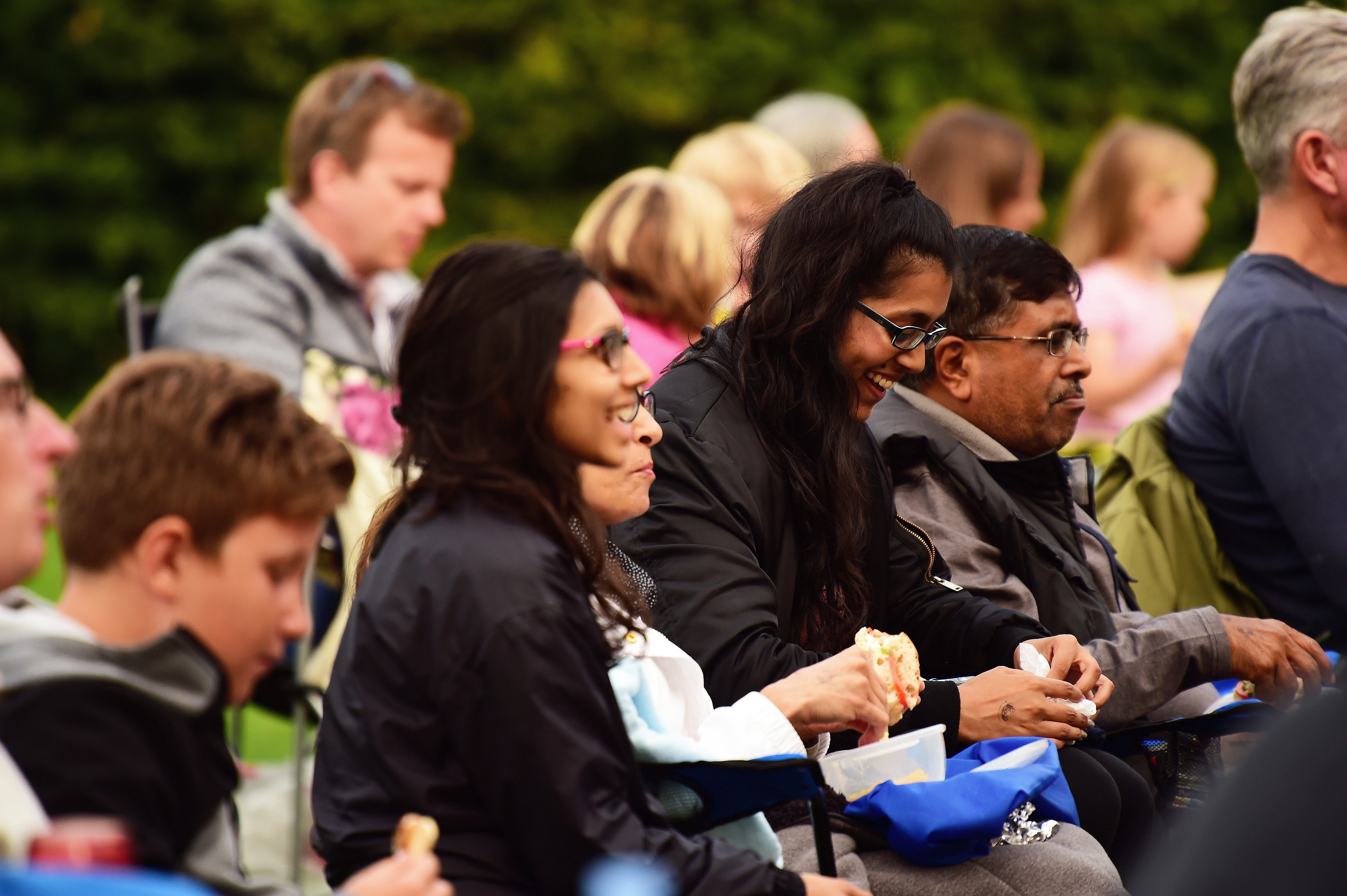 A number of people sitting with picnics.