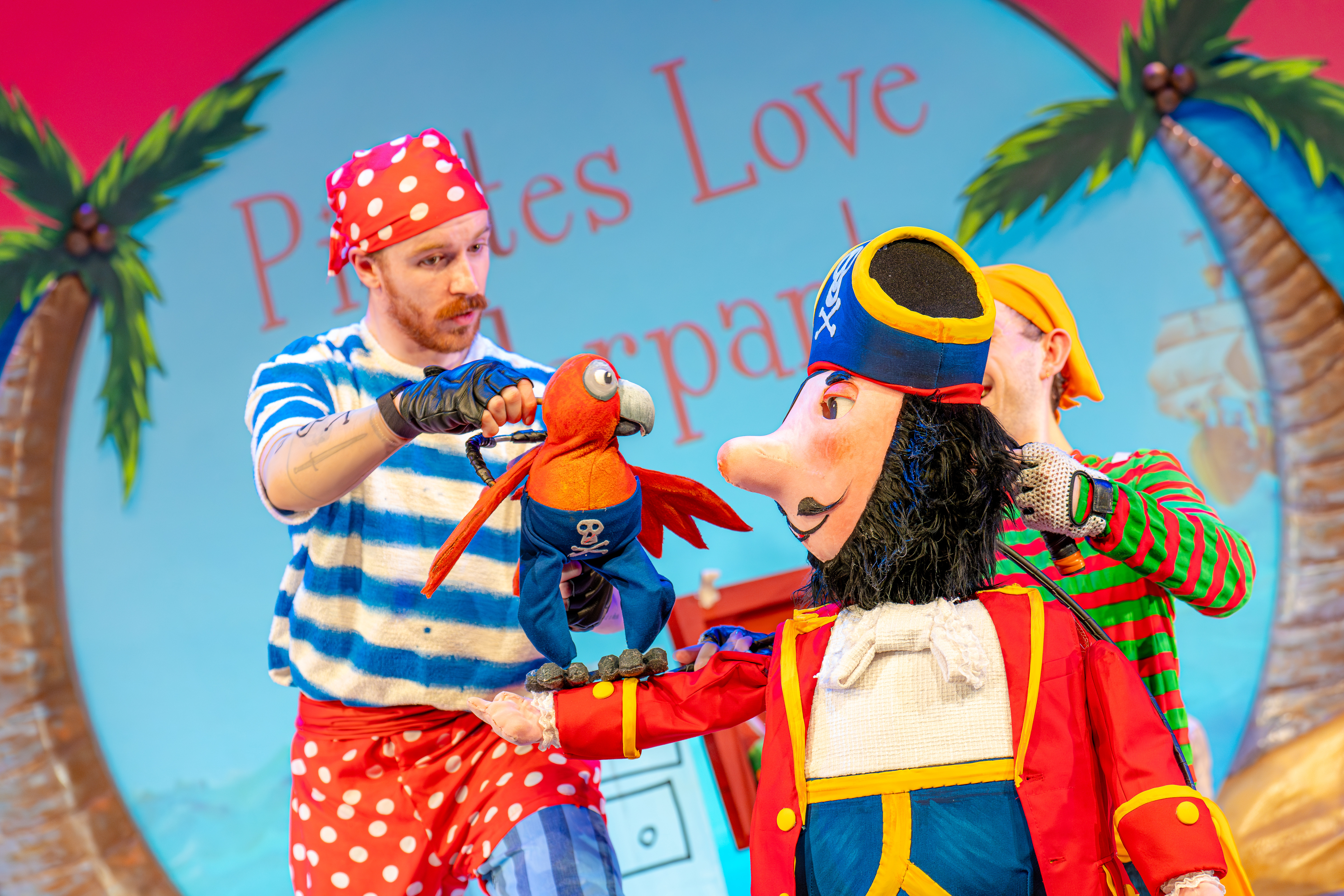 Two people with a pirate puppet and parrot puppet.