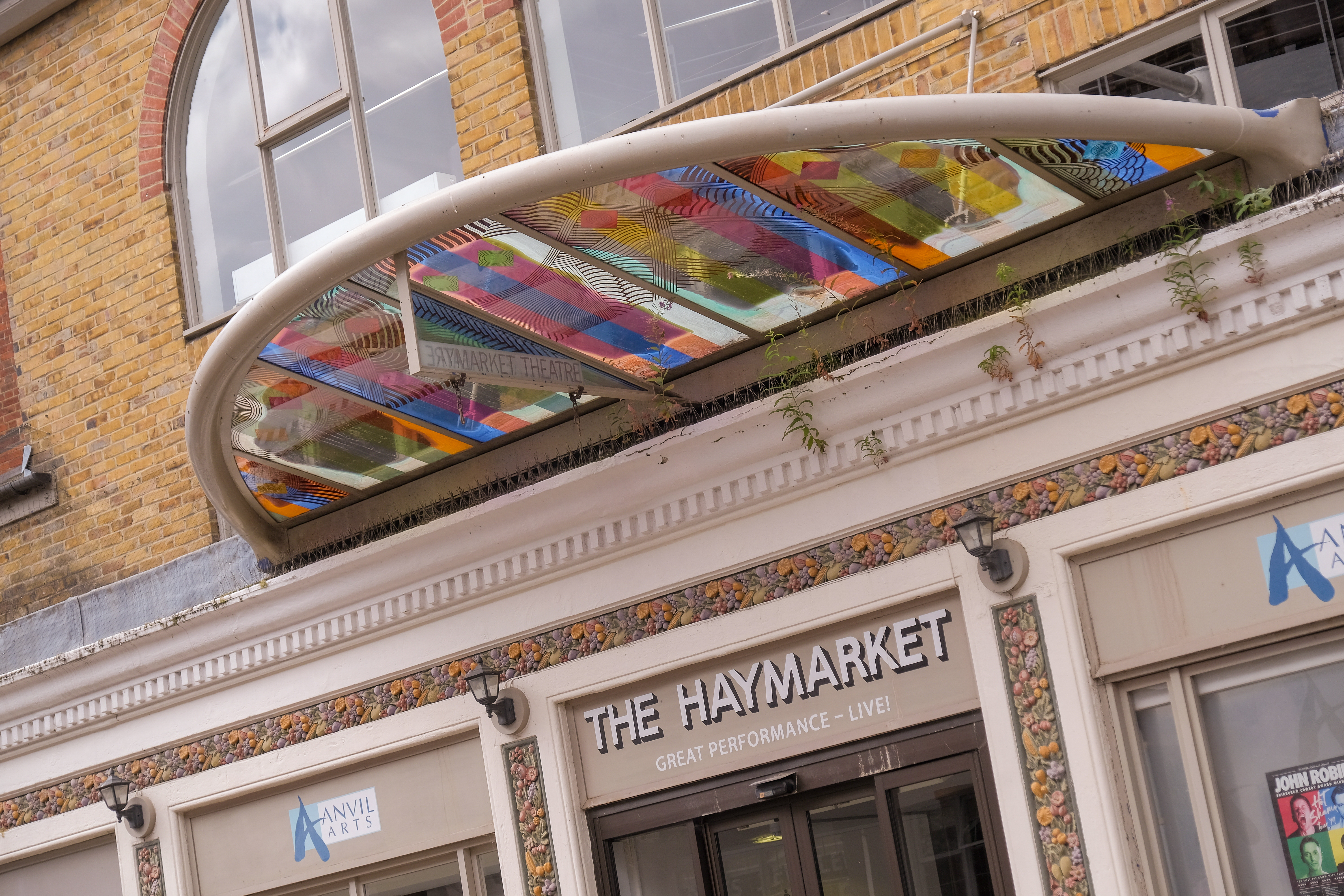 The outside of the theatre. A canopy of metal and different coloured glass.