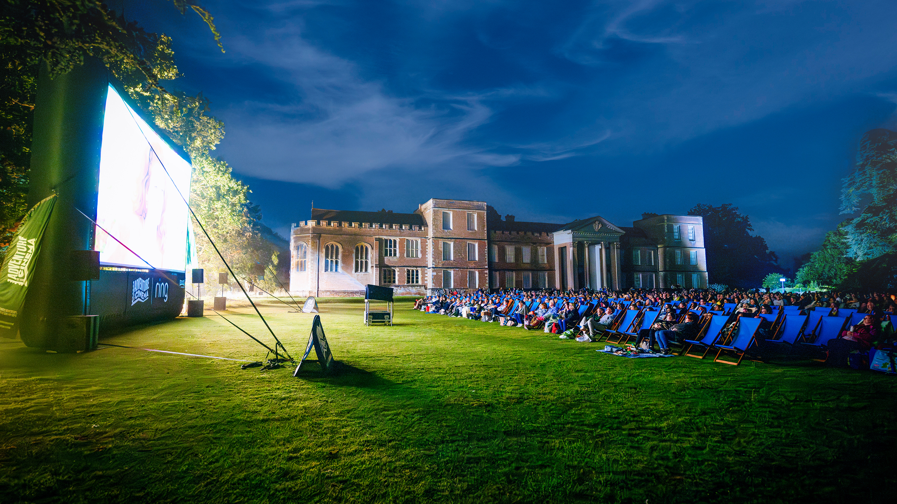 A screen placed infront of the Vyne. With lots of people and deckchairs