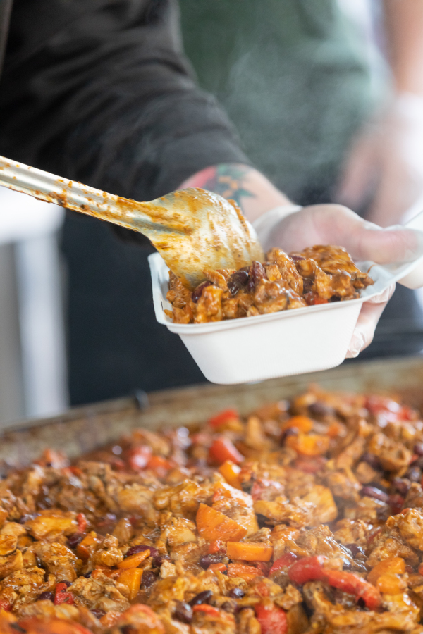Street food being added to a takeaway box