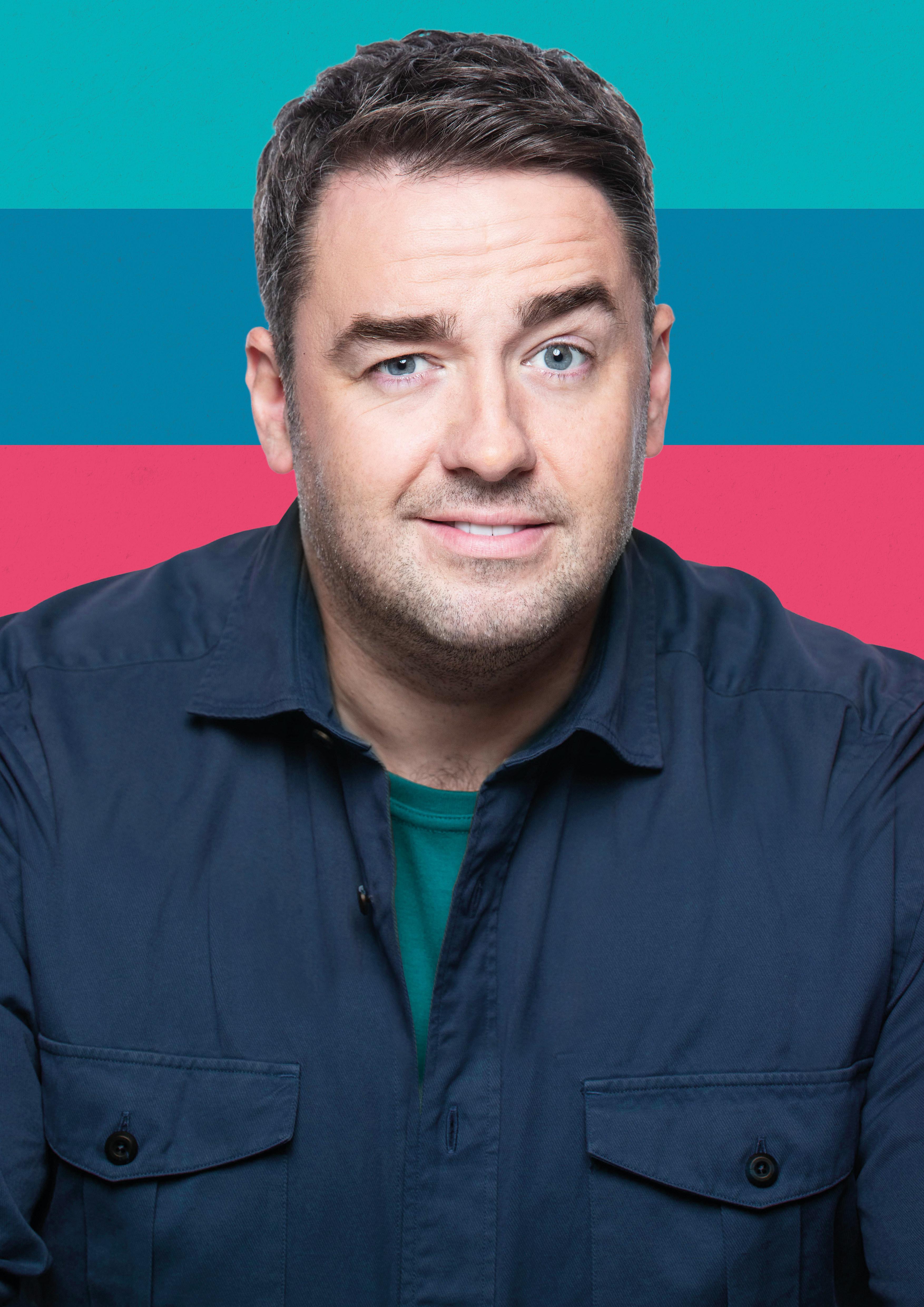 An image of a man looking straight at the camera wearing a navy shirt. The background is stripy pink, blue and teal.