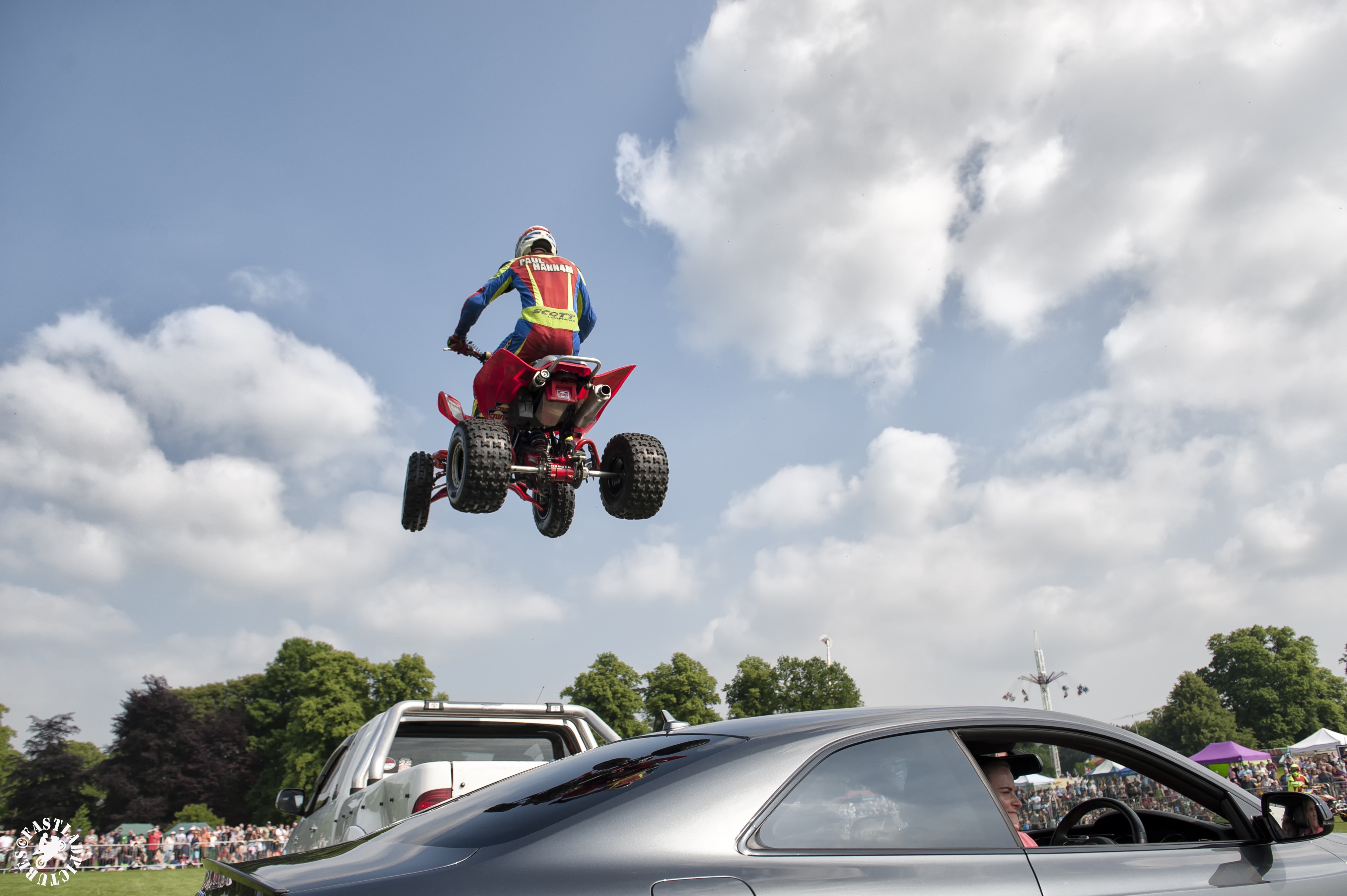 A pereson on a quad bike jumps over cars