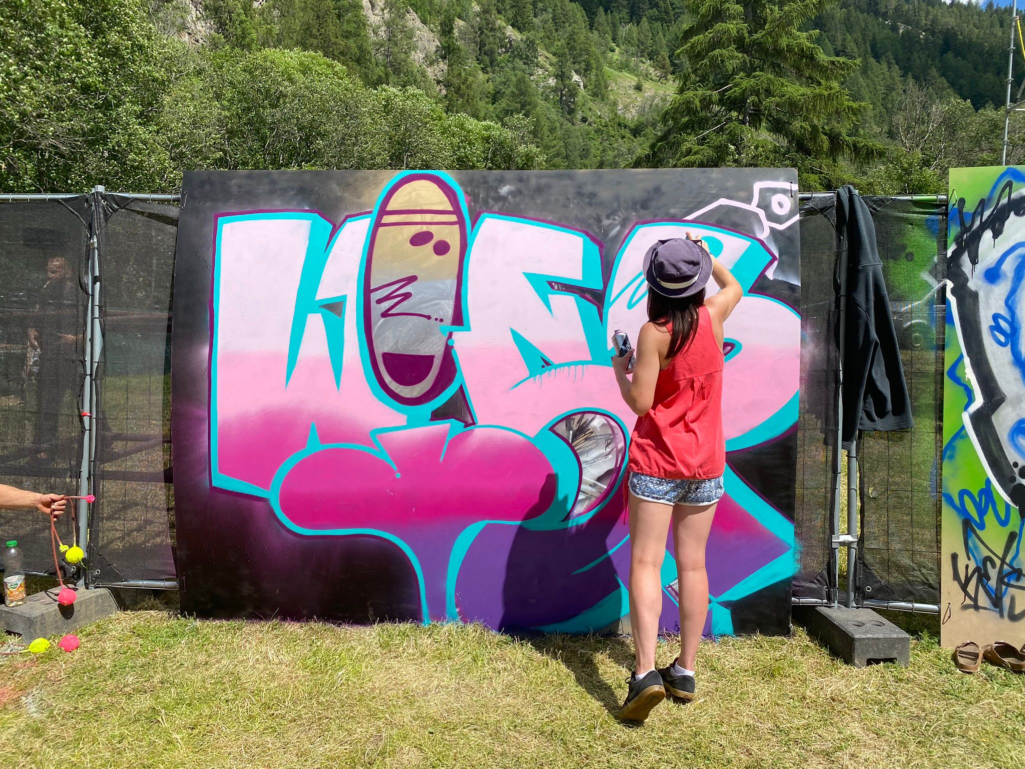 A female paints graffiti on a wooden board.