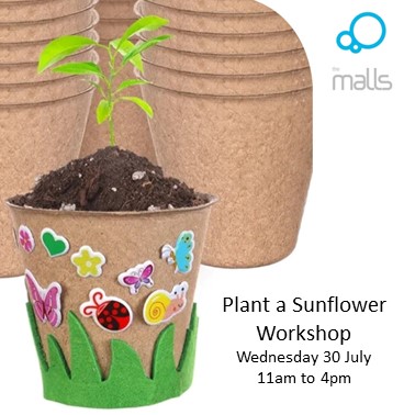 A handmade brown plant pot with a green shoot inside the soil. Cartoon bug stickers cover the pot.