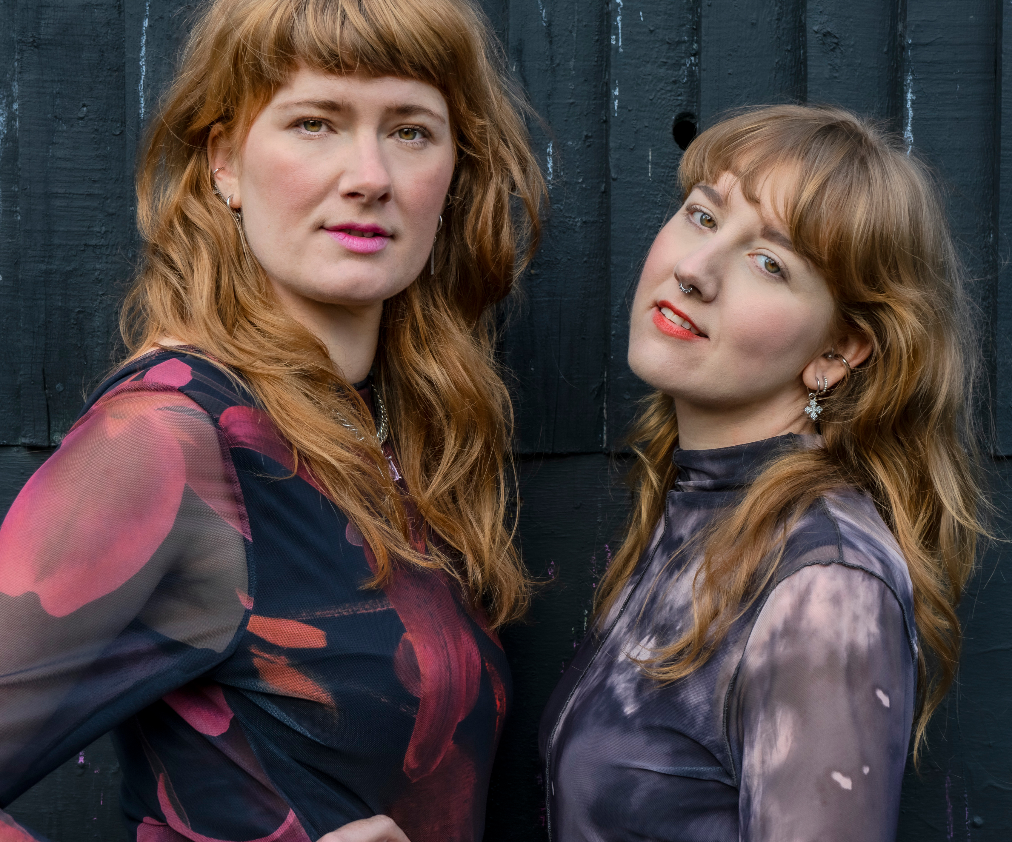 Two women stood side by side. They have fringes and dresses.