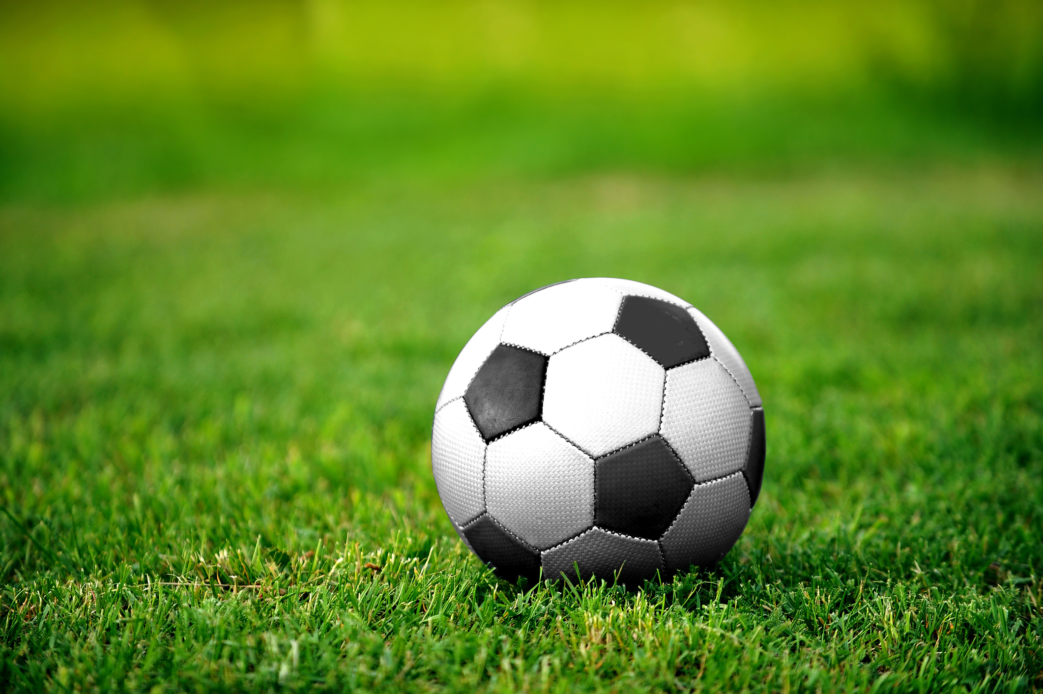 A black and white football on grass.