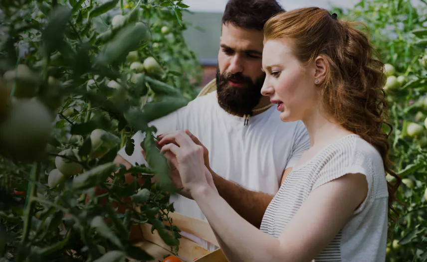A picture of two people surrounded by plants.