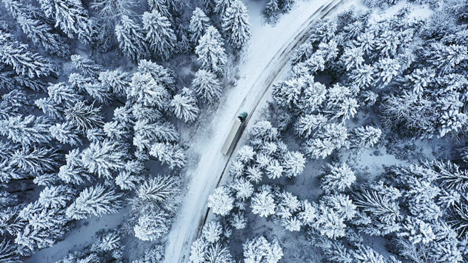 Un camion du Groupe Morneau, en vue aérienne, parcourant les routes enneigées du Québec.