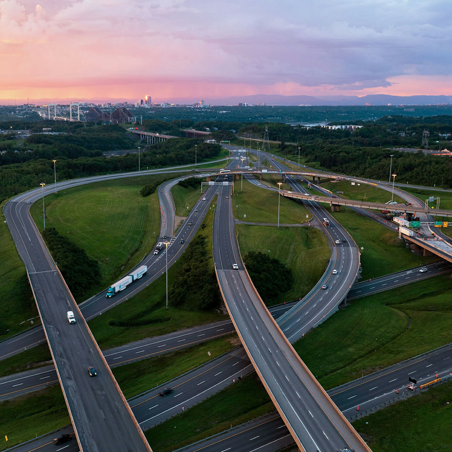 Un camion du Groupe Morneau parcourant une jonction d’autoroute du Québec en été.