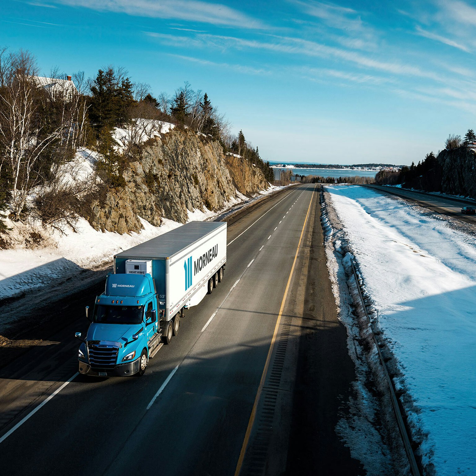 Un camion du Groupe Morneau, en vue aérienne, parcourant les routes du Québec en hiver.