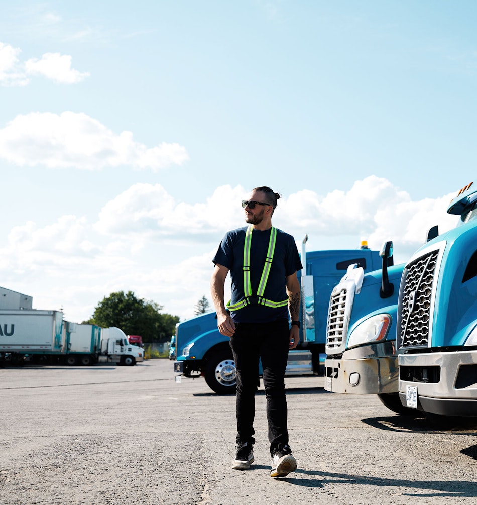 A Groupe Morneau driver walking past trucks parked at a terminal.