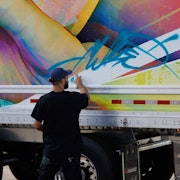 Artiste Fluke travaillant une fresque sur la remorque d'un camion pour le 80ème anniversaire Morneau