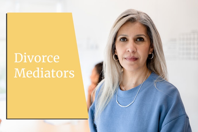 A divorce mediator looks at the camera while her clients talk in the background