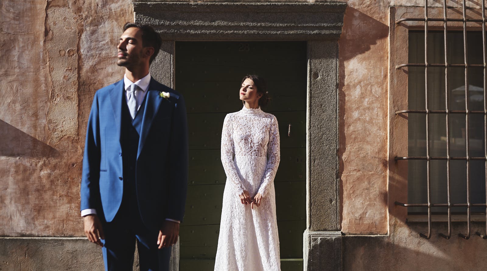sposo e sposa che guardano verso il sole vestiti da sposi davanti a edificio antico italiano