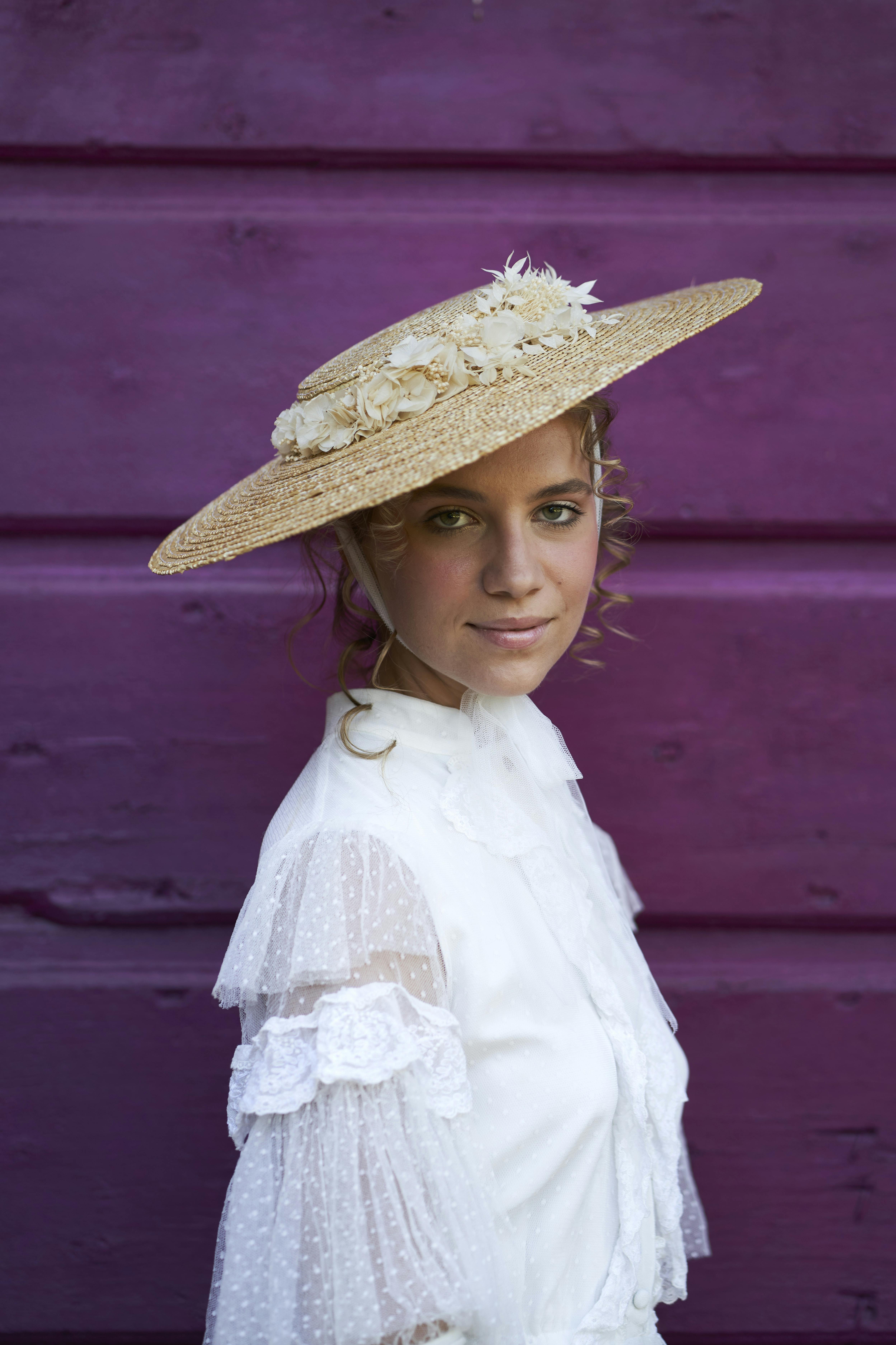 bride dressed as bride wearing a hat in front of a purple wooden door