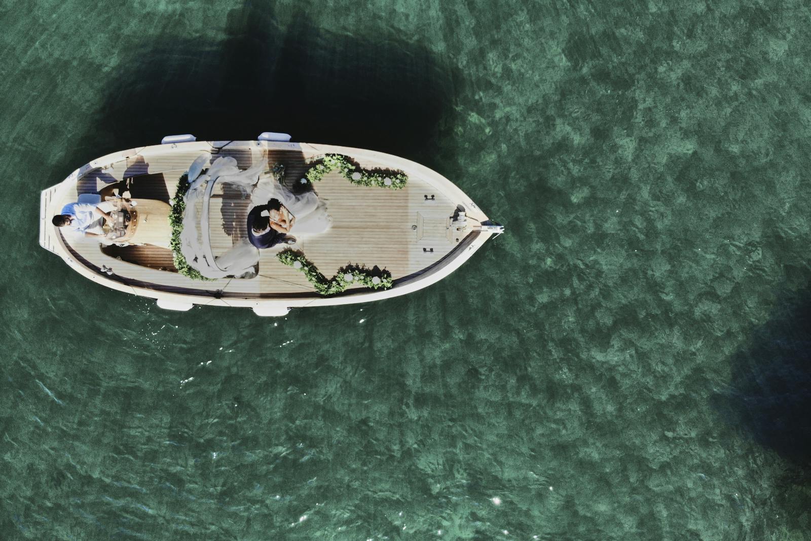 aerial view drone of bride and groom getting married on a boat in the middle of a lake