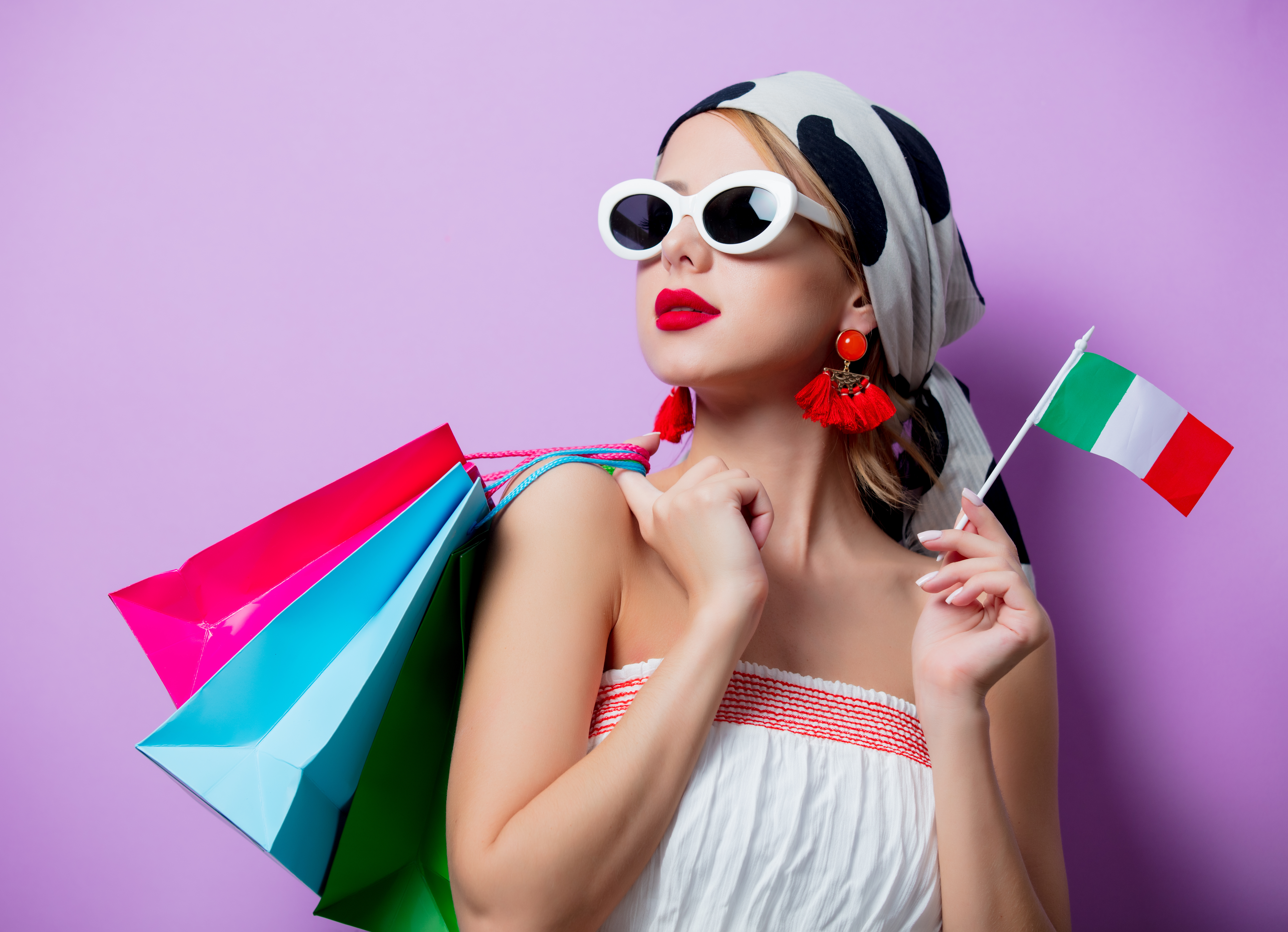 Girl with shopping bags and with sunglasses holding italian flag