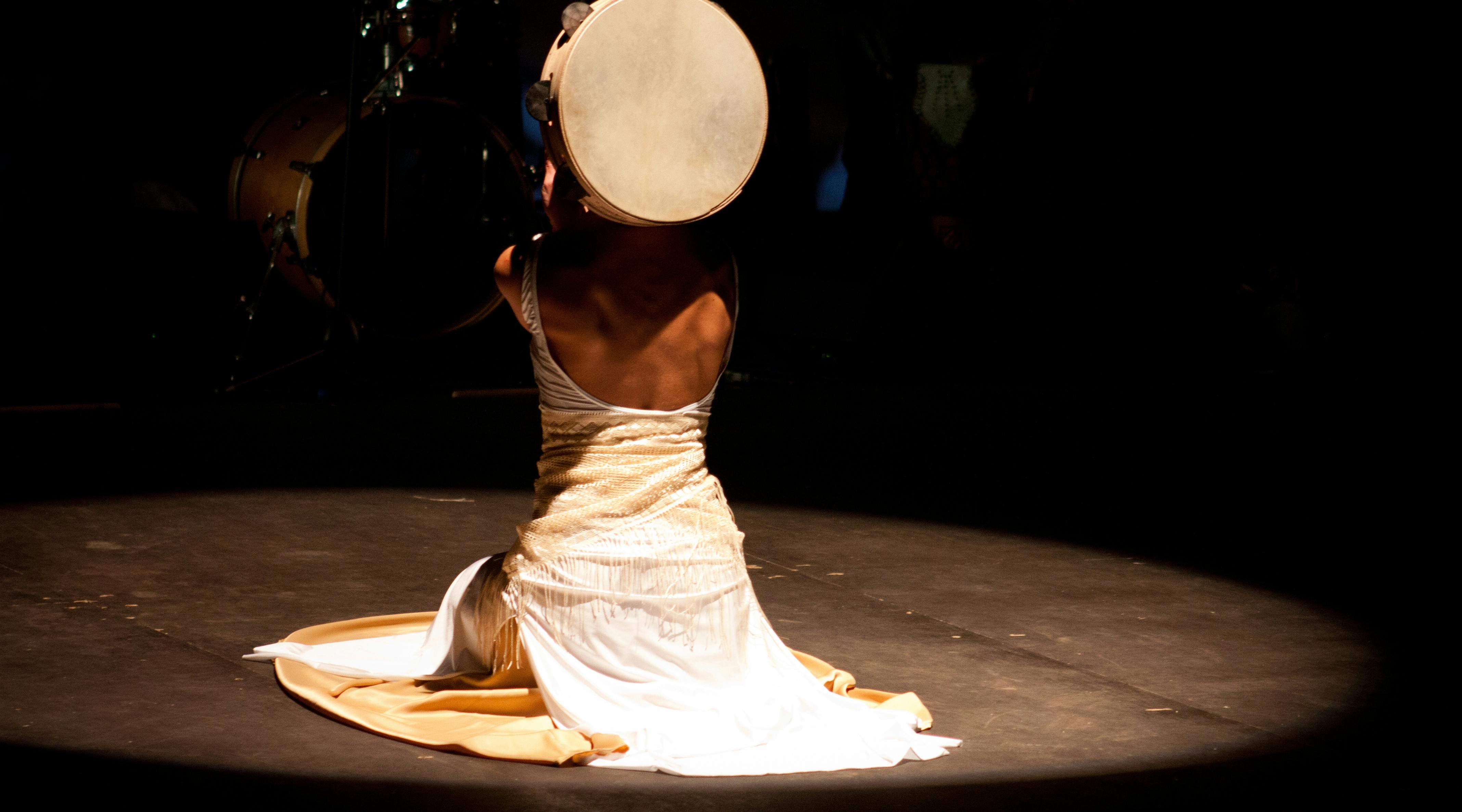 woman sitting on her knees on a stage while playing drums