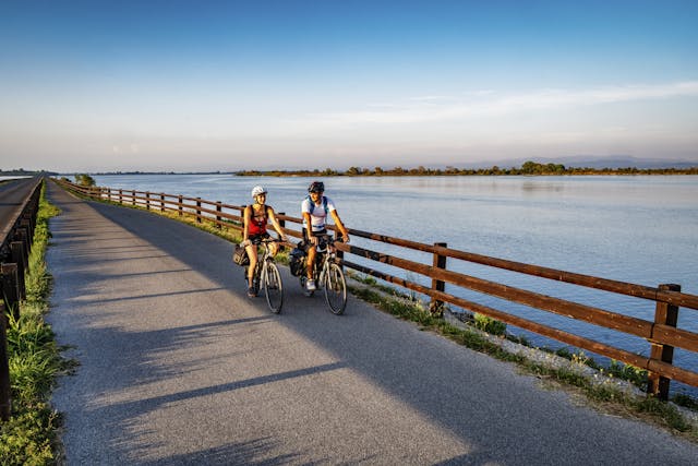 Persone in bicicletta con mare sullo sfondo