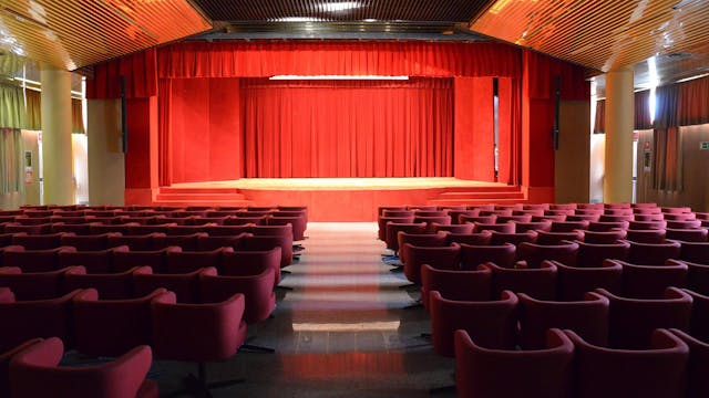 Sala riunioni con sedie rosse e palco