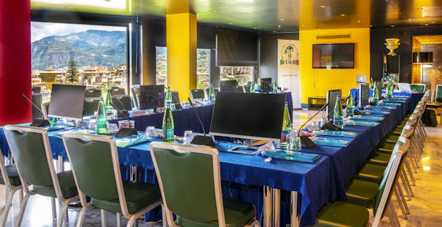Sala riunioni disposta a ferro di cavallo con tavolo blu e sedie verdi