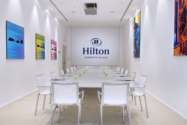 Meeting room with chairs, table and white walls and some hanging pictures