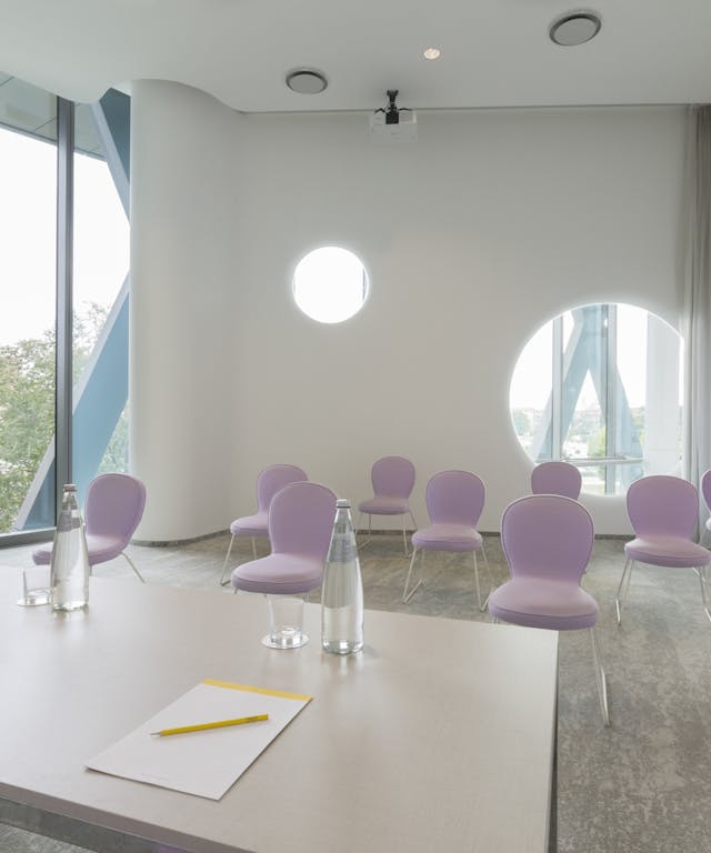 Sala riunioni con sedie rosa e pareti bianche