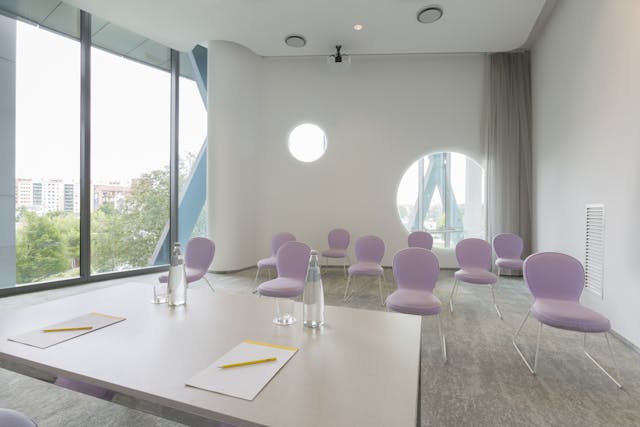 Sala riunioni con sedie rosa e pareti bianche