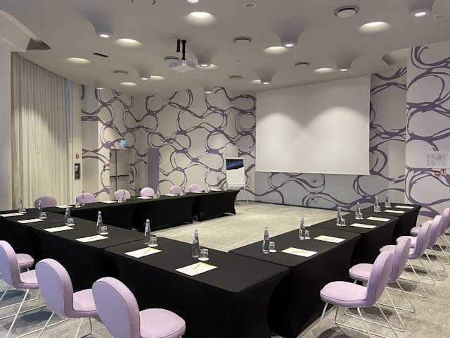 Sala riunioni con tavolo nero e sedie bianche