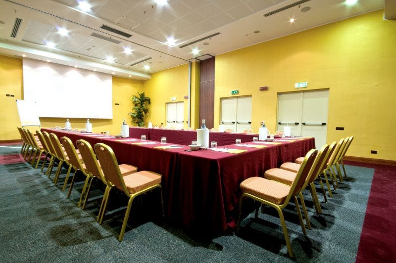 Sala meeting-tavolo rosso-sedie-pareti gialle