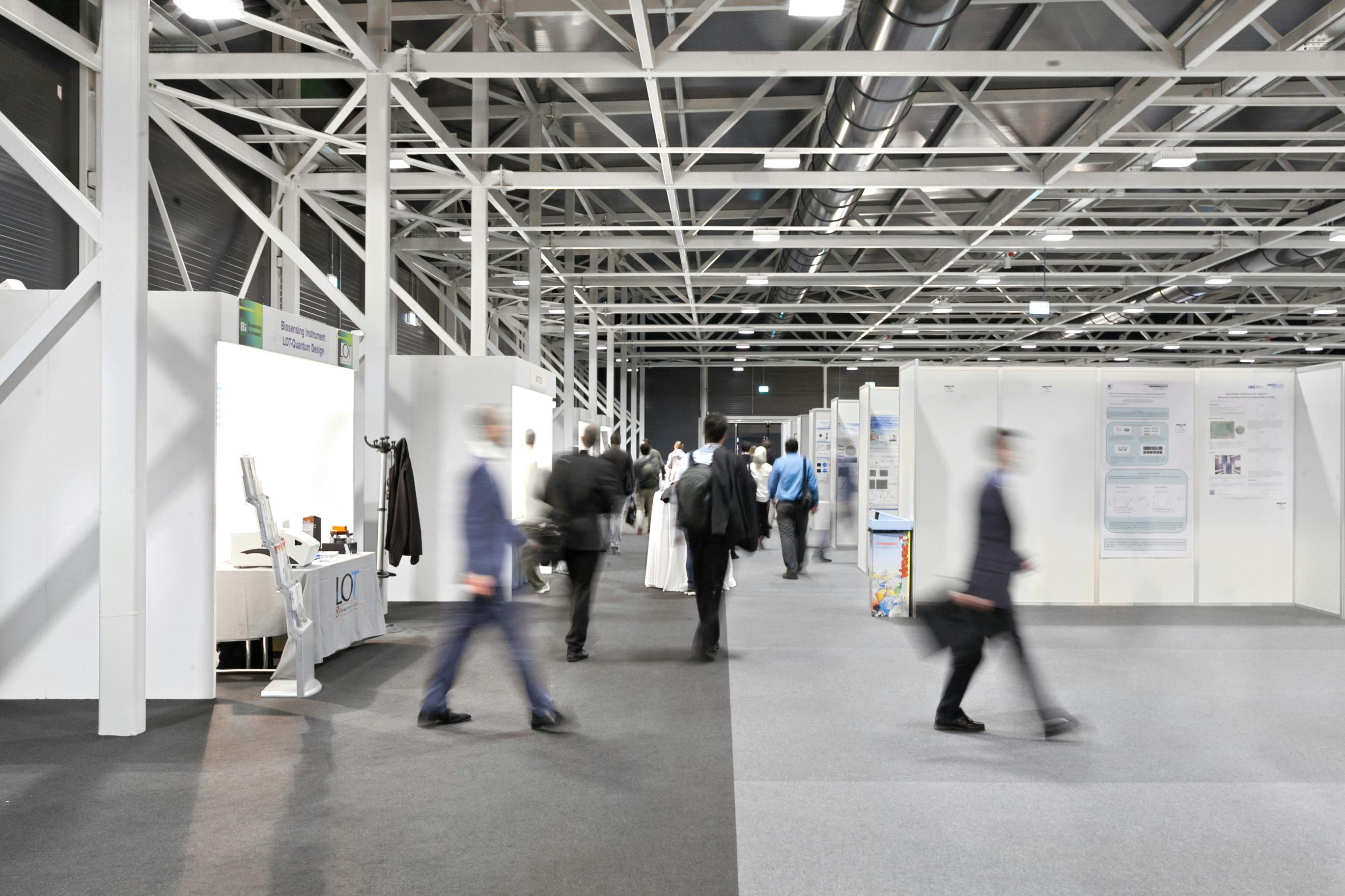 Sala exhibition con stand e persone in movimento