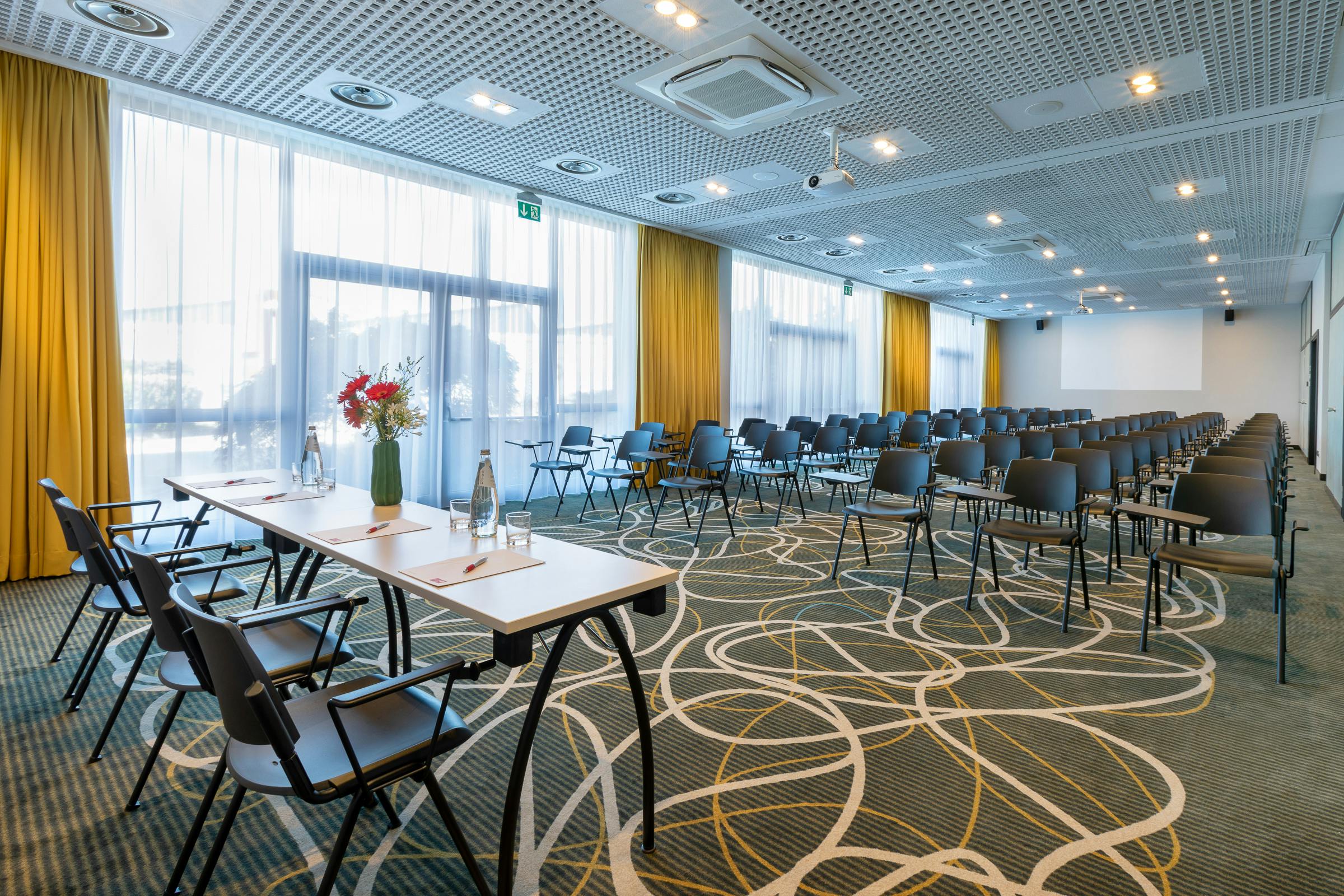 Sala meeting con sedie nere e tavolo con fiori