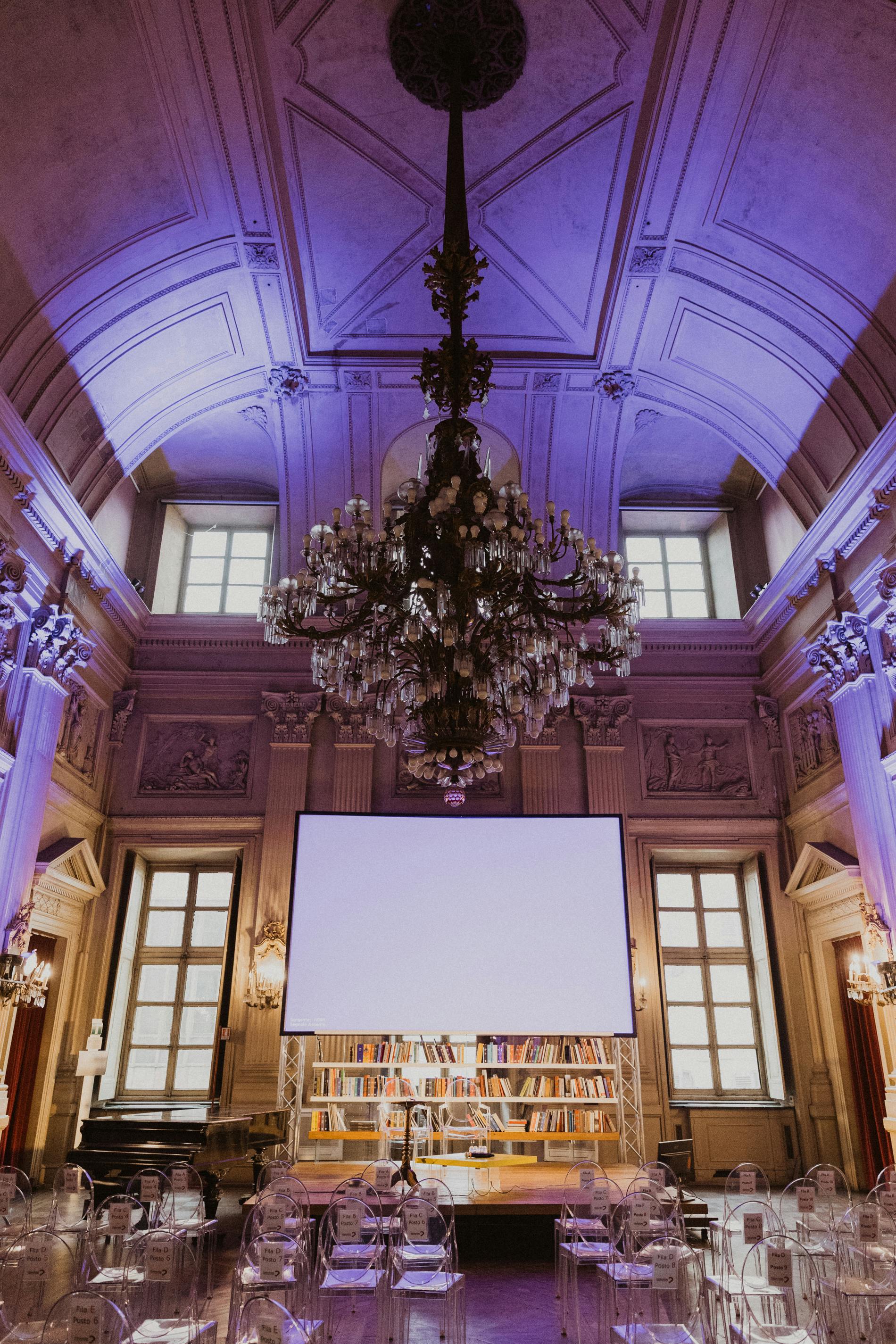 salone con sedie, schermo e lampadario